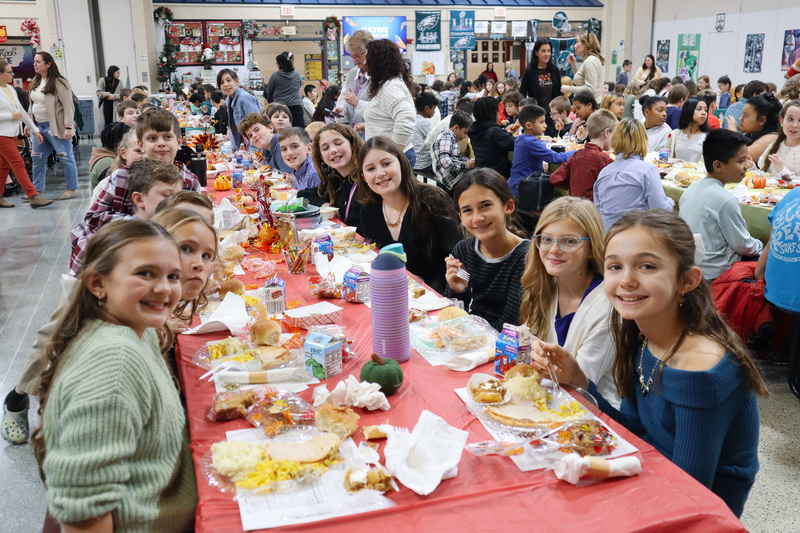 Children enjoying a meal at a long table with autumn-themed decorations.