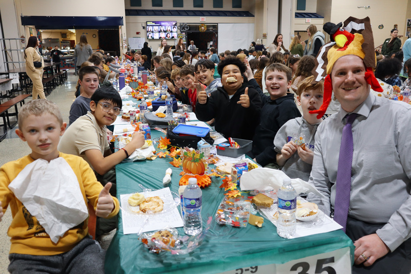 Children enjoying a meal at a long table with autumn-themed decorations.