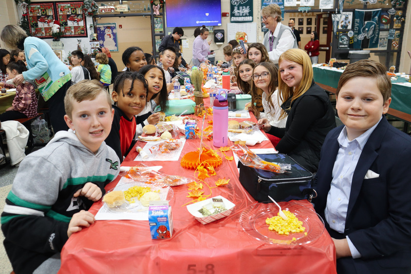 Children enjoying a meal at a long table with autumn-themed decorations.