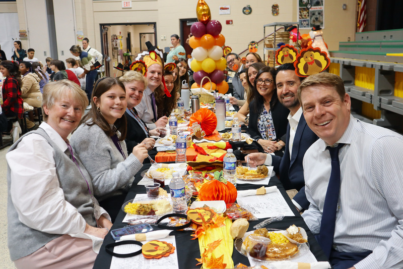 Teachers enjoying a meal at a long table with autumn-themed decorations.