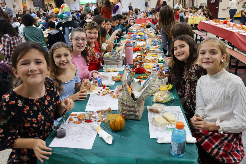 Children enjoying a meal at a long table with autumn-themed decorations.