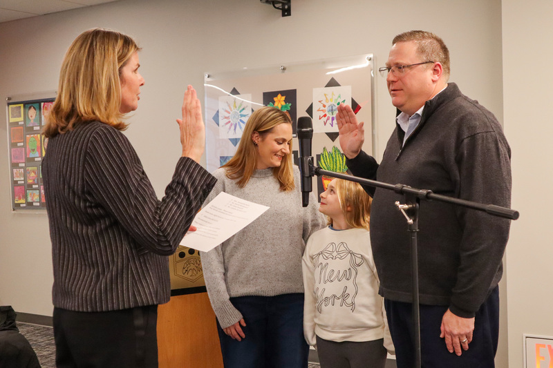 A man being sworn in during a ceremony with his family present.