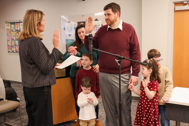 A man being sworn in during a ceremony with his family present.