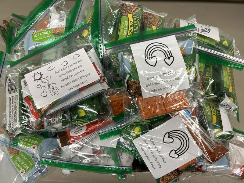 Zip lock bags packed with various snacks, including positive notes for recipients with cute graphics.