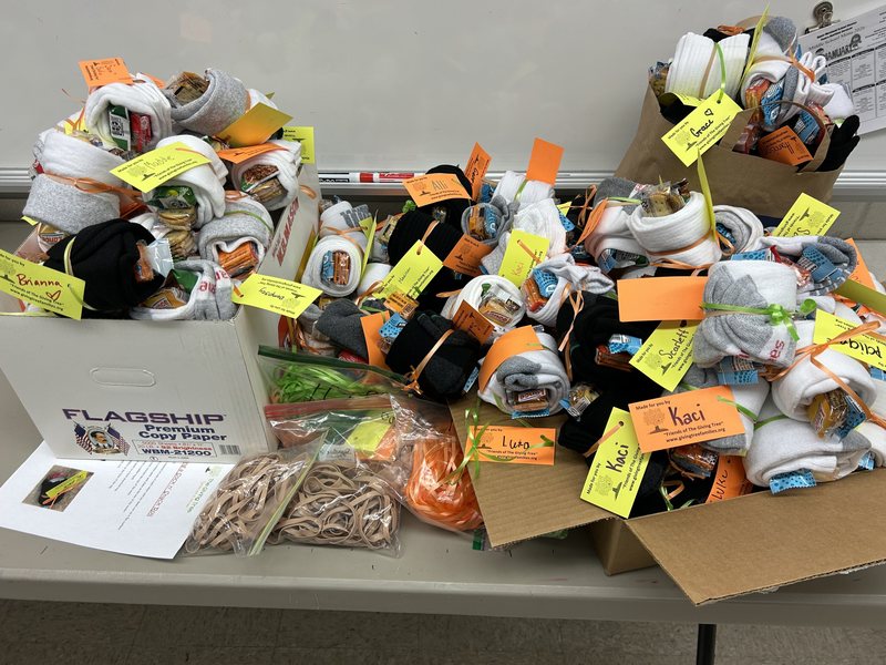 Rolled socks with items and tags in boxes on a table.