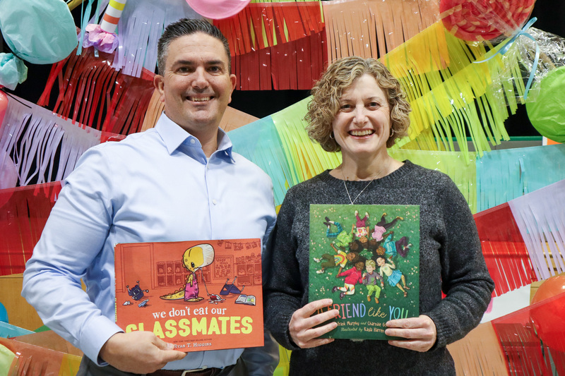 * Dr. Elliott and Dr. Cannon stand in front of a colorful backdrop and hold children's books