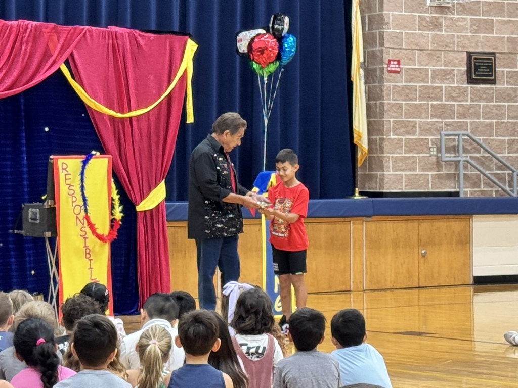 A magician shows off a magic trick with help from a student. 