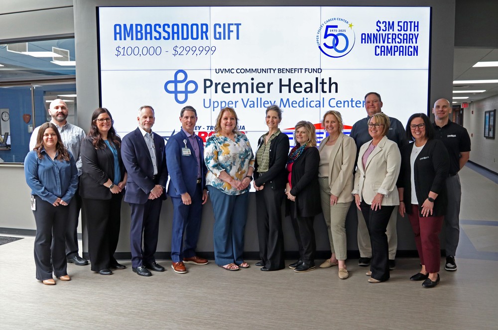 leadership from premier health pose with uvcc leadership in front of donor board