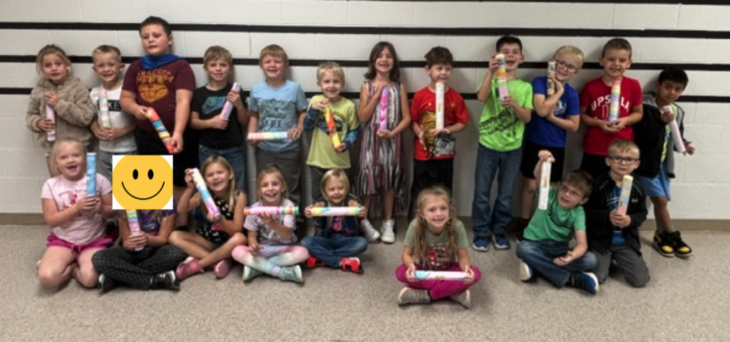 First graders holding rain sticks.