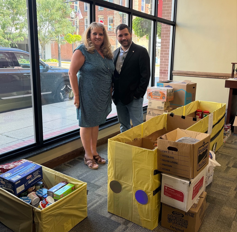 Picture of First Community Bank representative and Anthony McDaniels along side of food donations for Upshur County Students.