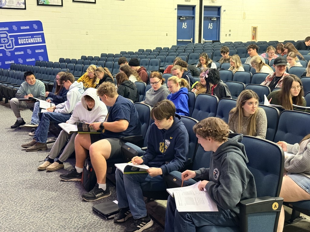 Students at the test prep session with books open in the auditorium working to be prepared for the SAT.