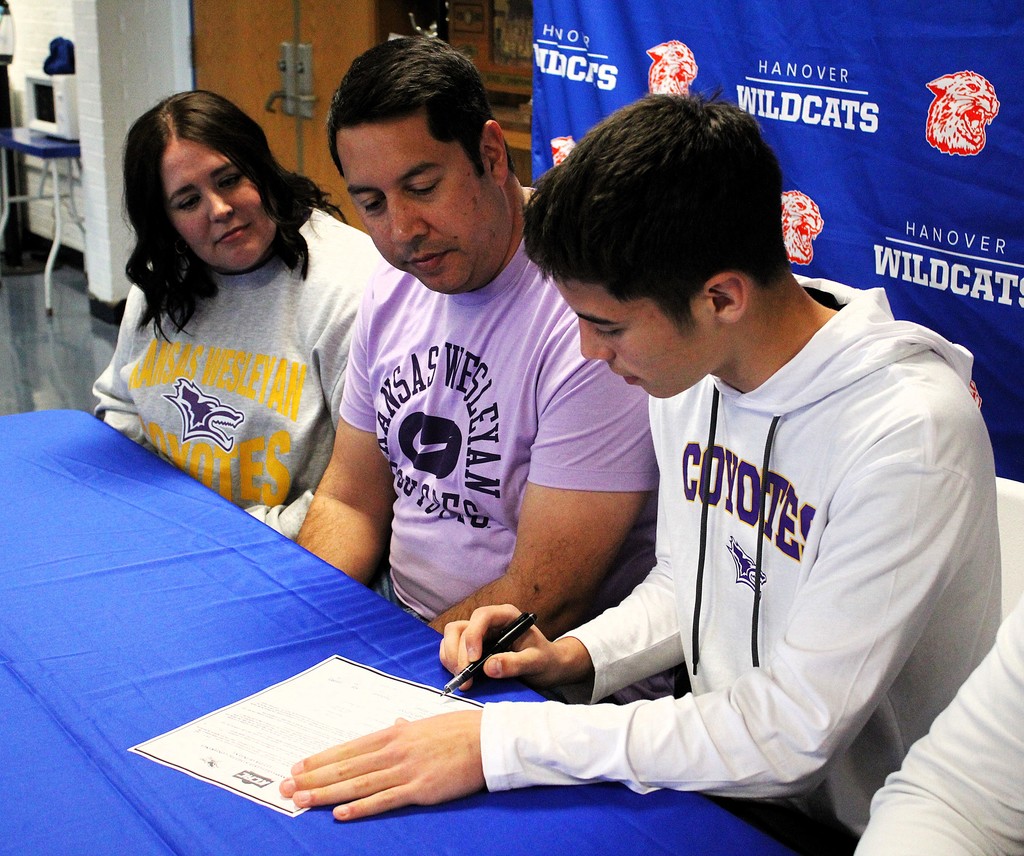 Braylon signs with parents, Chris and Renee, and Coach Cory Jensen looking on.