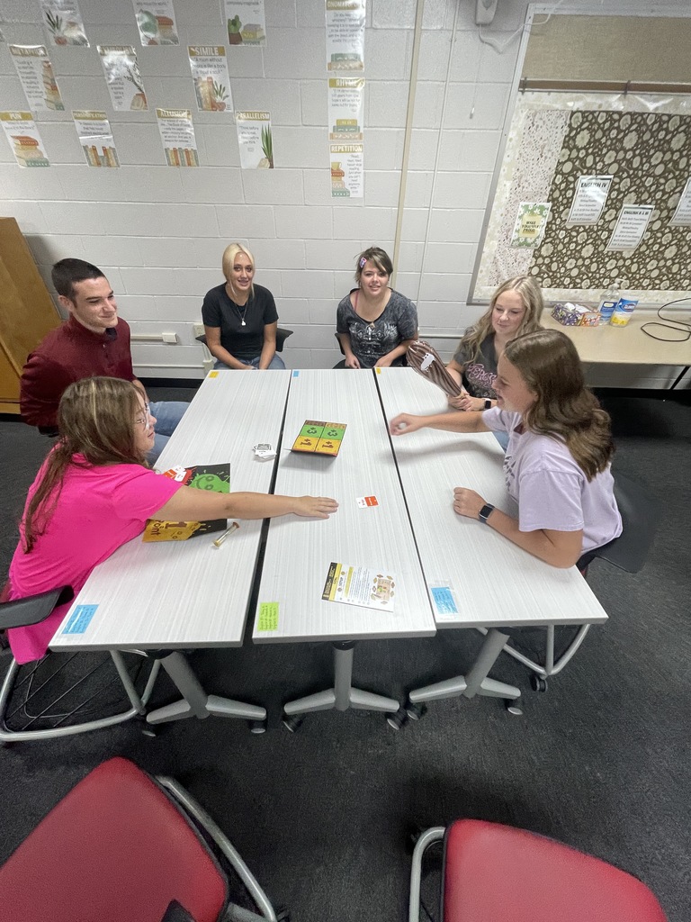 Picture of six students playing a game around a table.