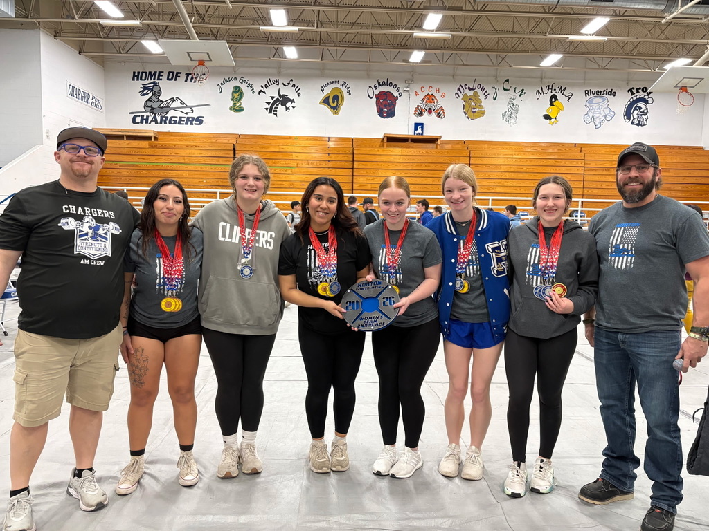 A group of seven people with medals standing together. Three women wear black pants, and four wear blue.