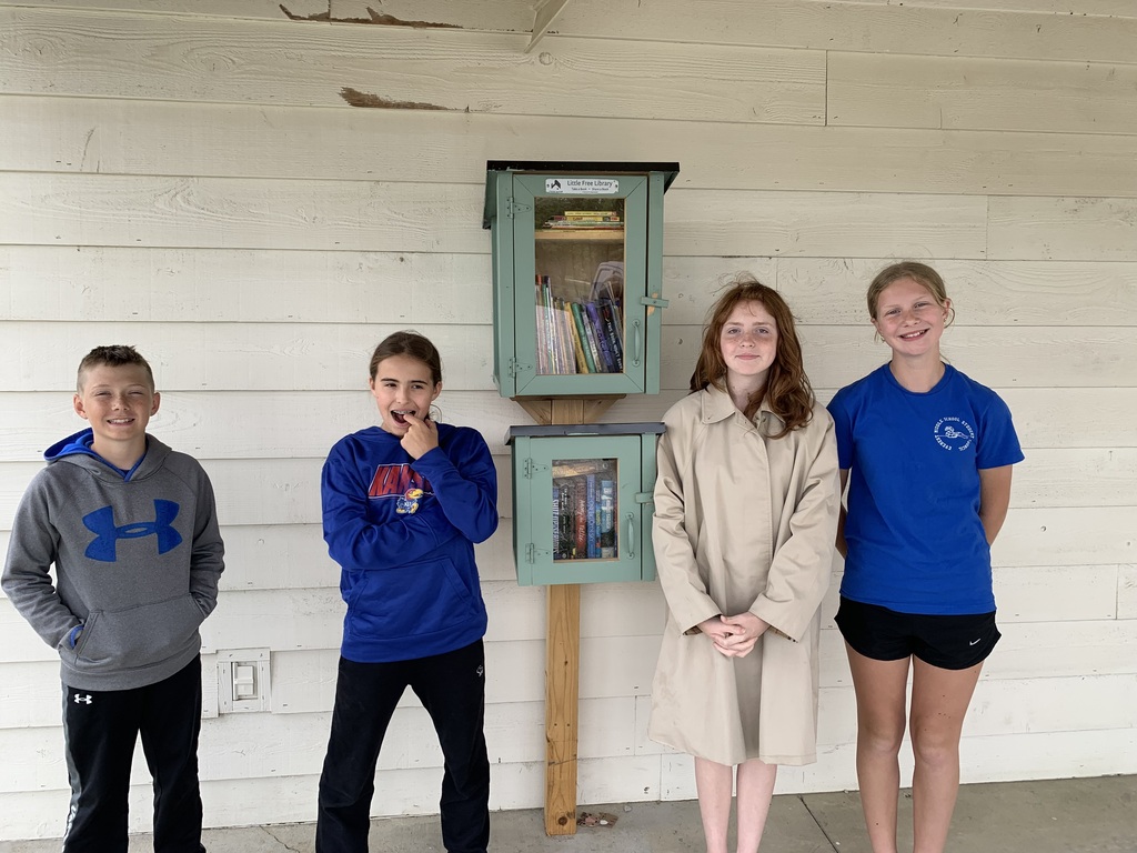 Four young people stand together, two girls and two boys, with a small green box behind them.