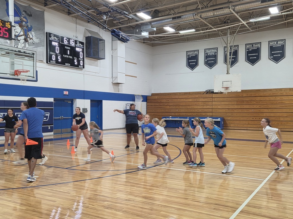 A group of people participate in a relay on an indoor basketball court, wearing sports attire and sneakers.