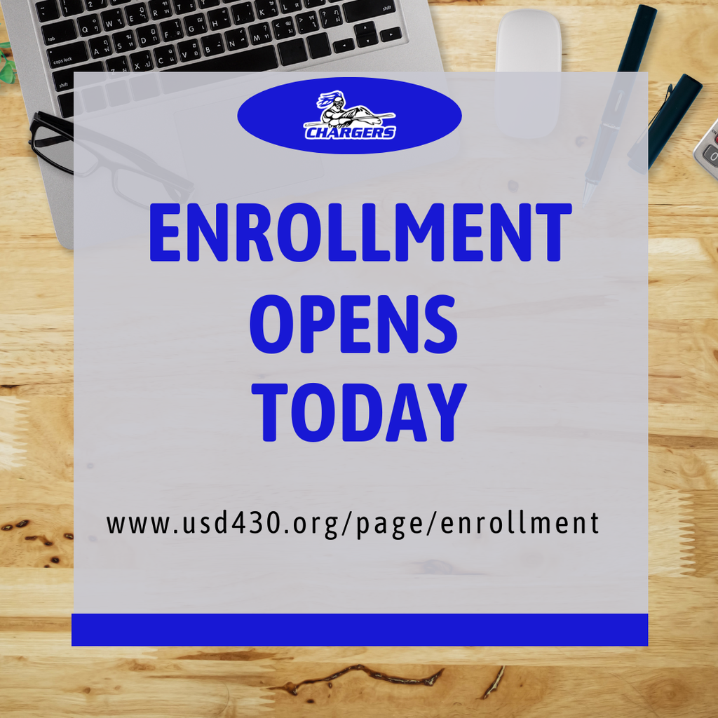 A sign with blue border reading "ENROLLMENT OPENS TODAY" on a wooden table with a laptop, mouse, and other objects.