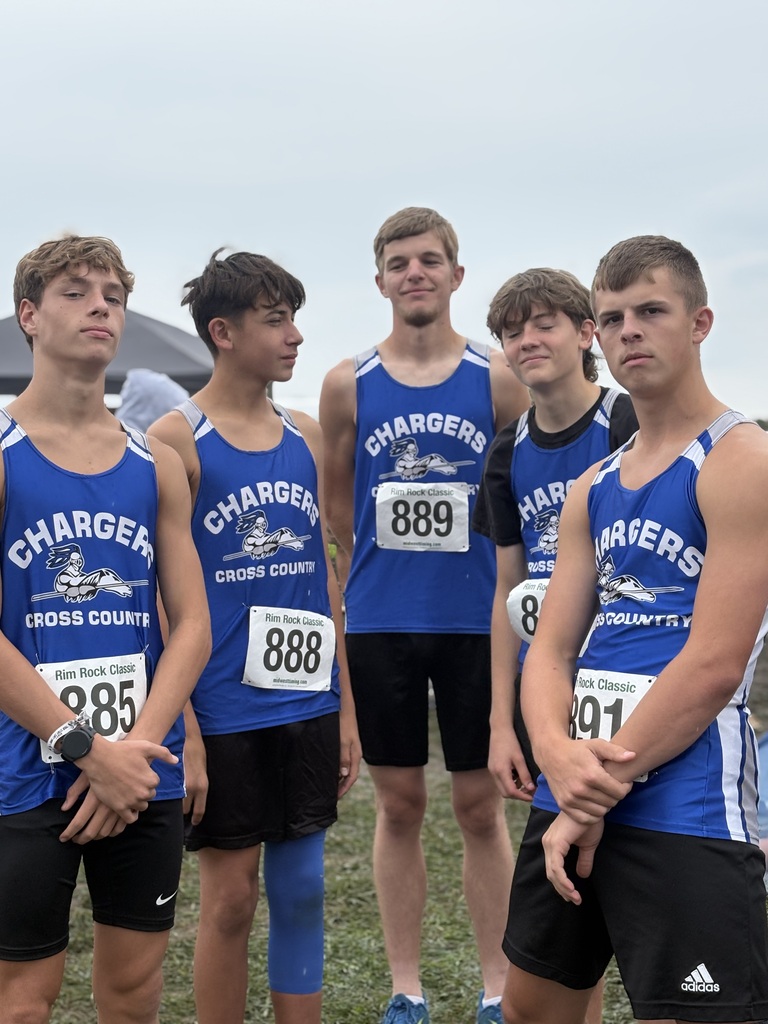 Five young men in blue jerseys with "Chargers" on them, numbers 889, 888, 891, and two others, stand on a grassy field.