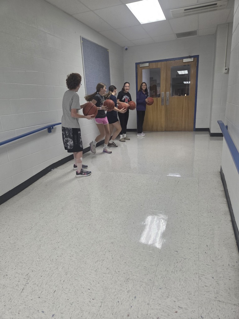 Five people with boxing gloves in a hallway with a white floor and white walls. One person stands in front.