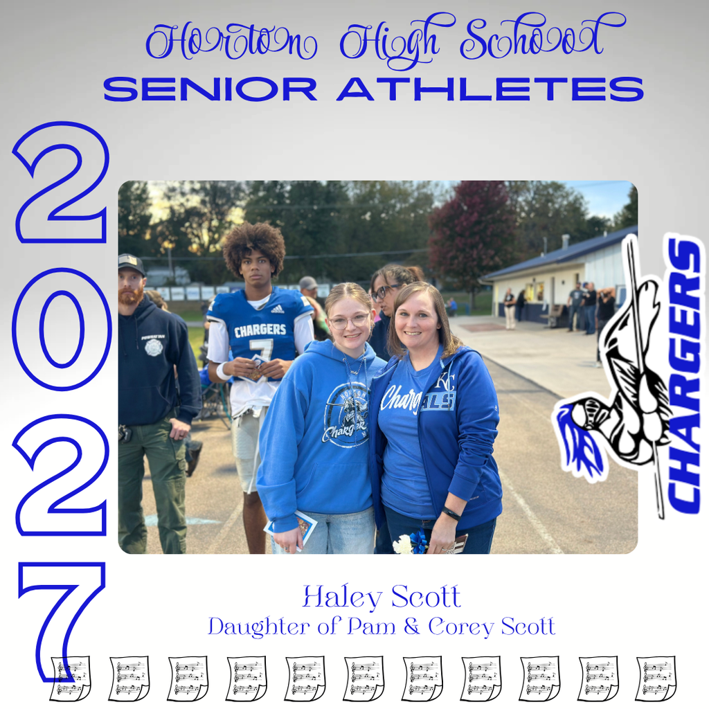 Two women stand with blue shirts; one holds a book. Behind them, a football player and others stand. Trees and a building are in the background.