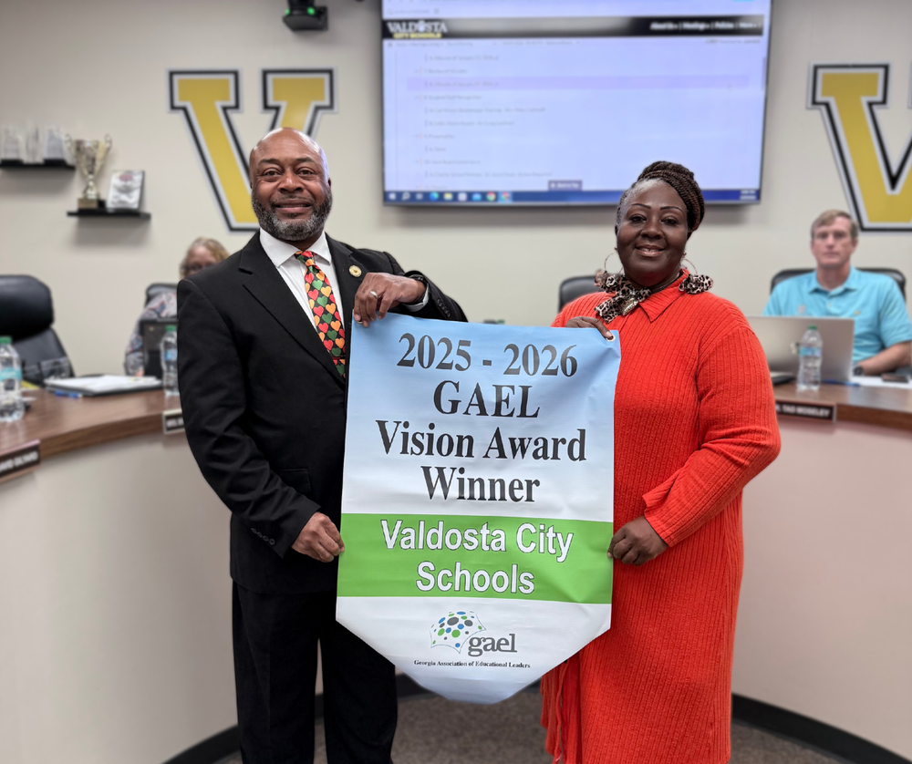 board chair holding award banner with superintendent