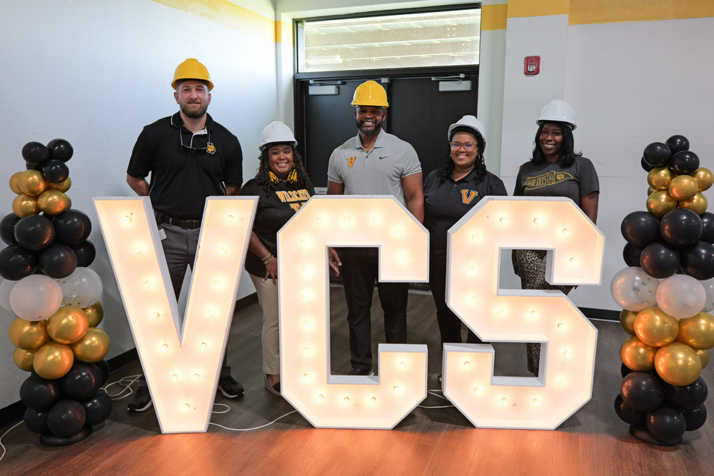 Group photo of SLM admin behind VCS Light up letters and balloons