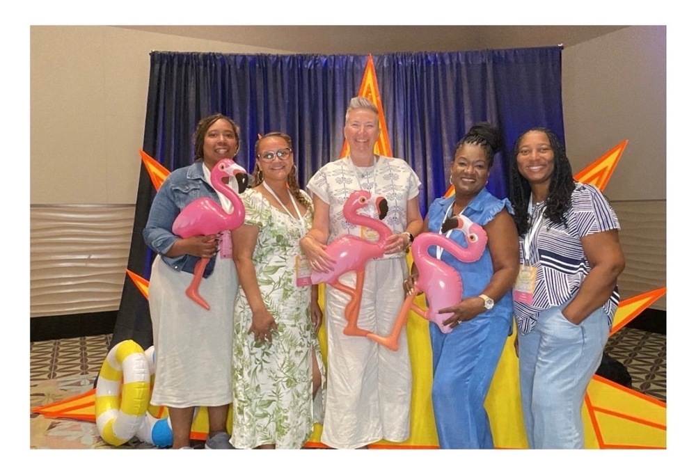 coaches smiling, holding blow up flamingos