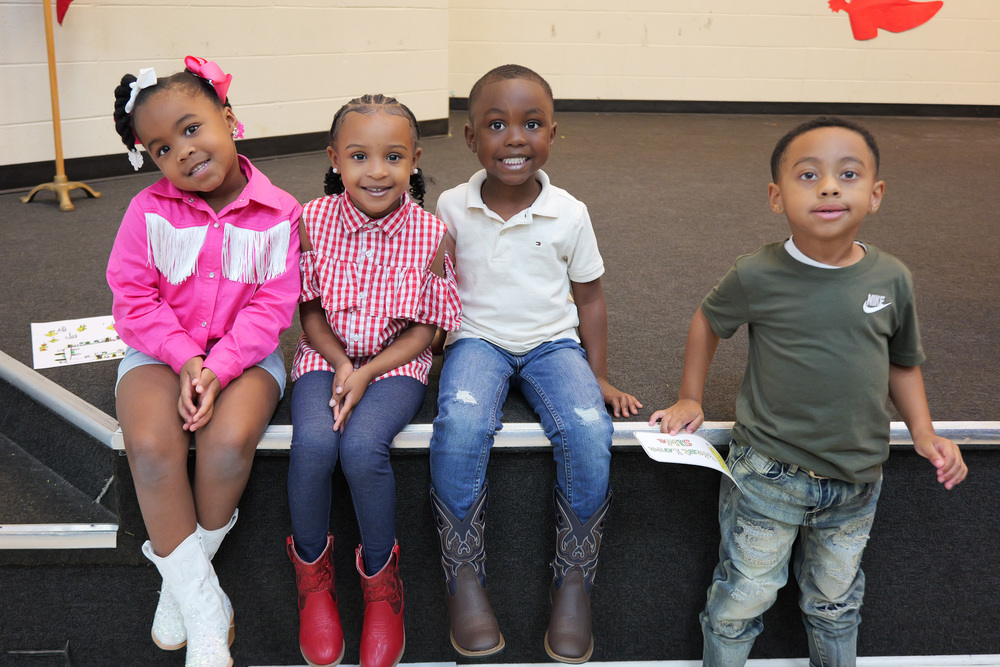 four students in their booths beside the stage, smiling