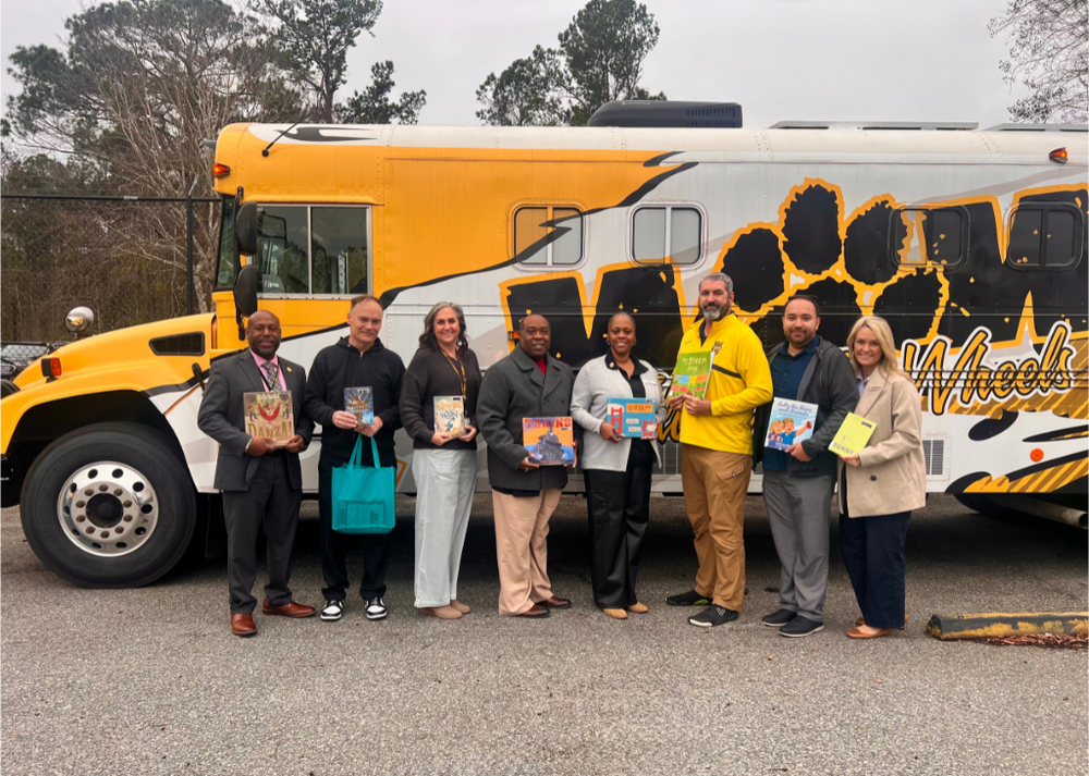 People holding up books in front of the WOW Bus