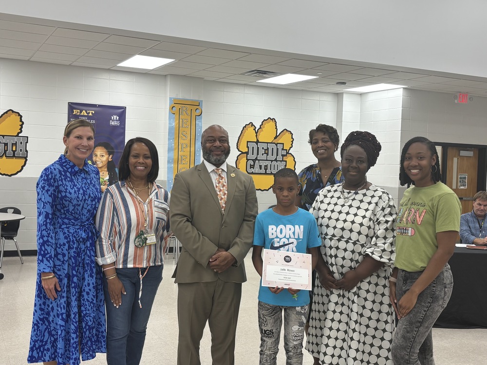 group photo with Jalik holding certificate and VCS staff and board chair