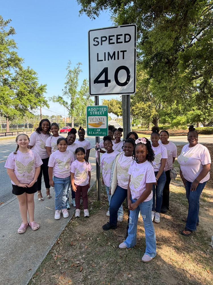 students and faculty standing in front of sign