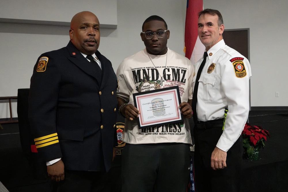Student with representatives from Valdosta Fire Department, holding certificate