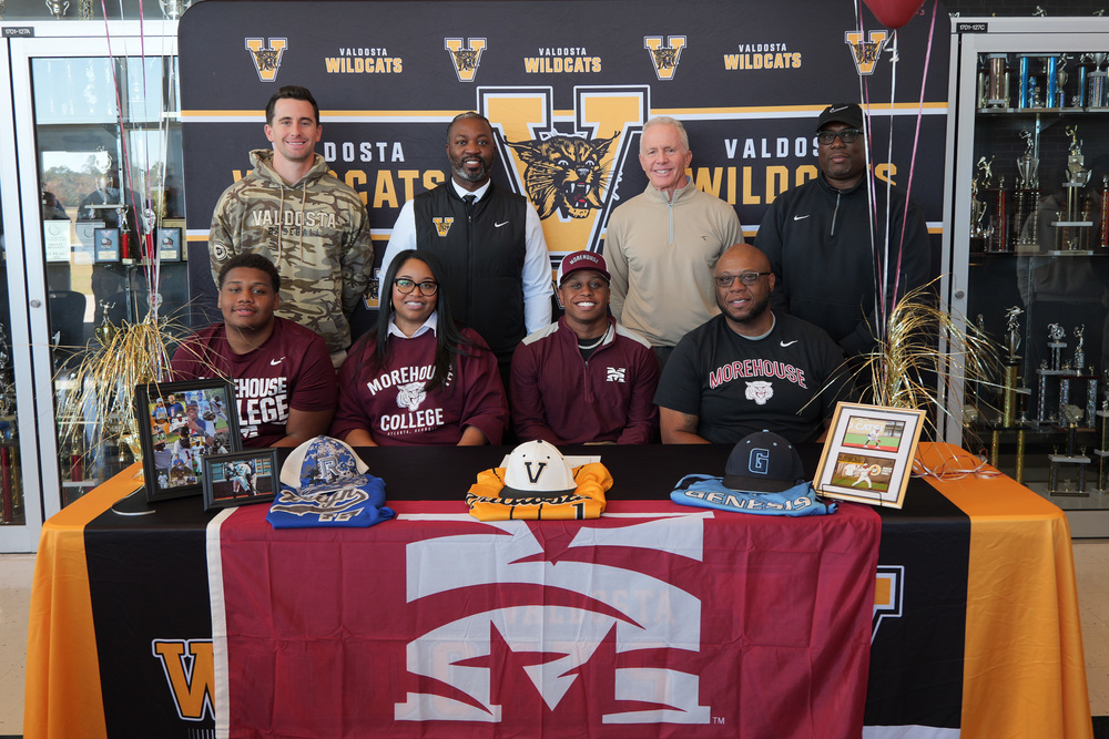 Student with family and coaches at signing table