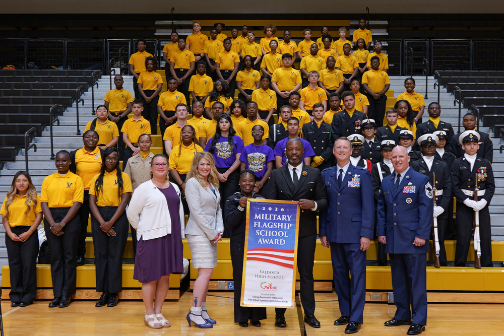 group of students with guest and Dr. Marshal, holding the military flagship school award banner