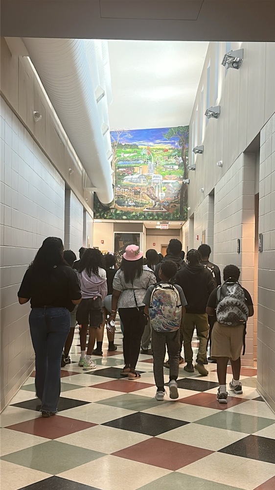 group walking in hall underneath art