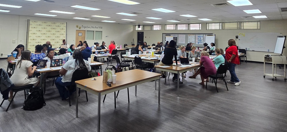 large photo of room where educators are collaborating at separate tables