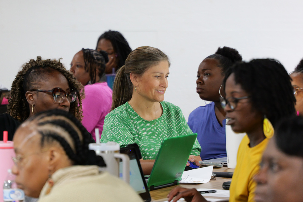 Staff participating in the training at computers, in center she is smiling