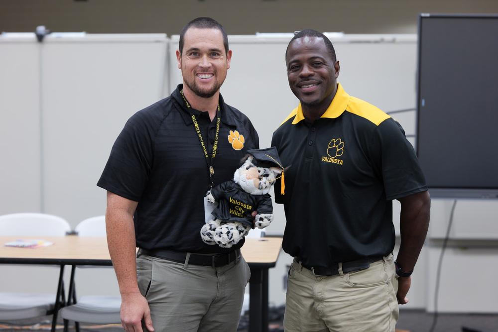 Mr. Crosby holding Willie the Wildcat next to Mr. Lewis, both smiling
