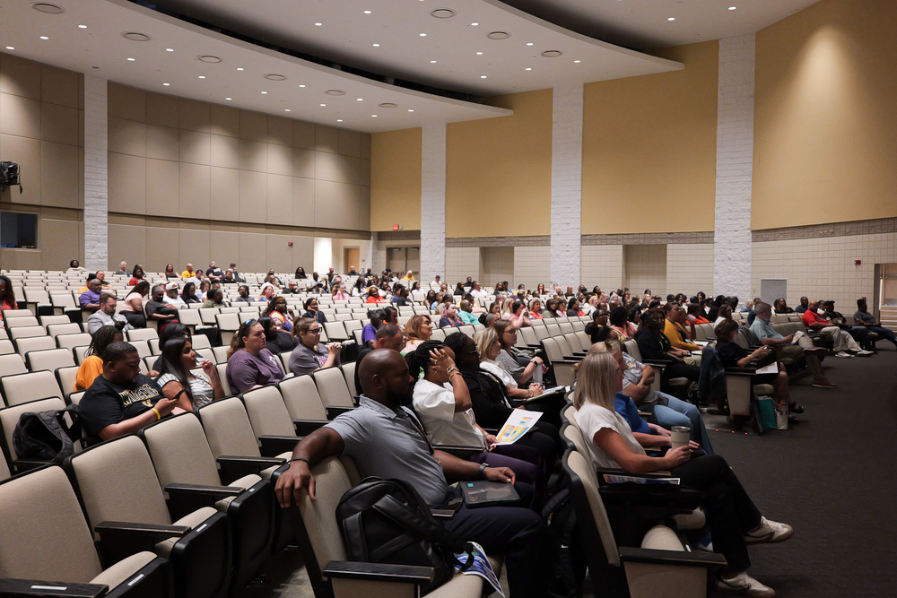 wide shot of auditorium with teachers sitting in the seats listening