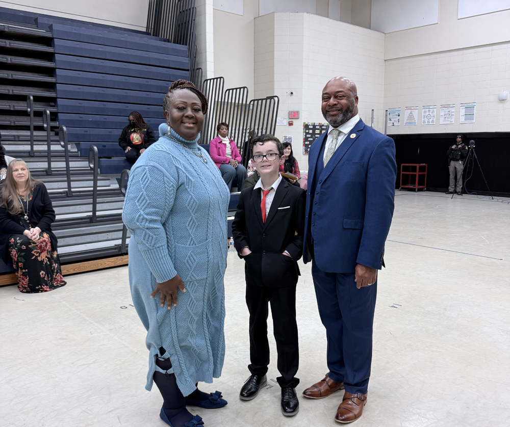 student standing with board chair and superintendent