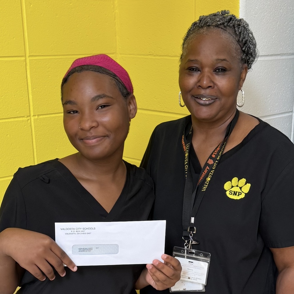 student holding envelope with staff member
