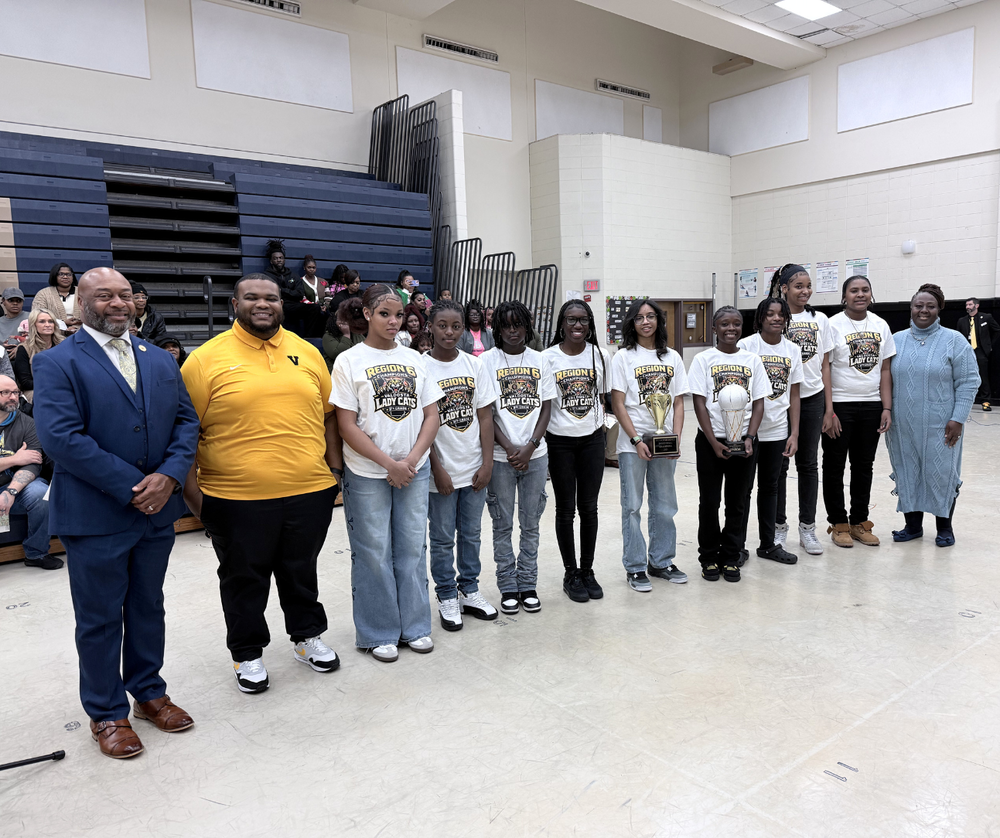 team standing with superintendent, coach, and board chair