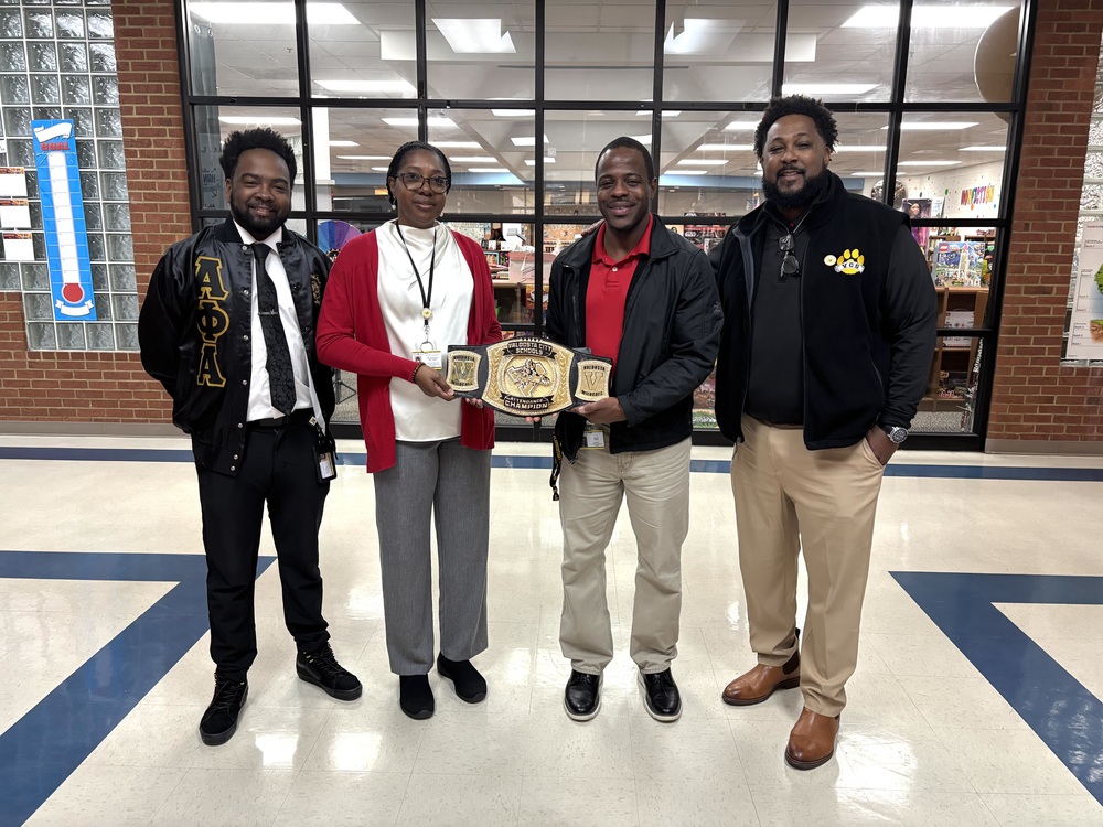 Group photo holding the belt that signifies JLL being champion