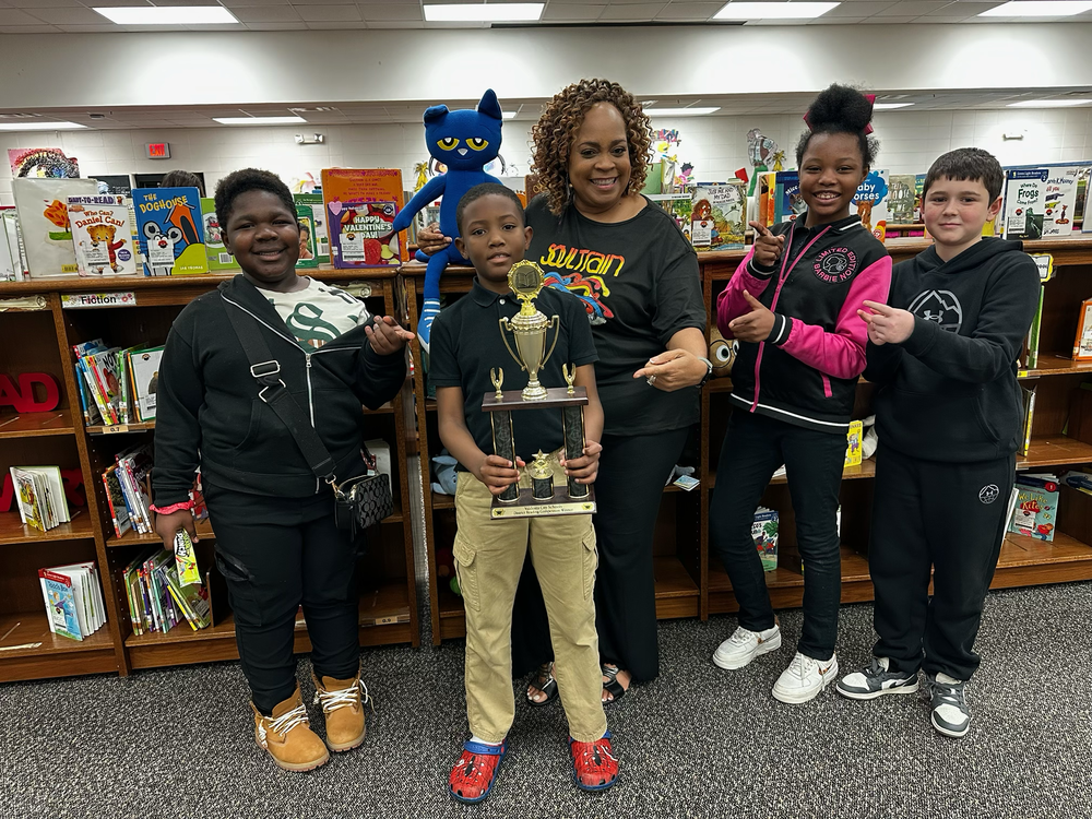 group photo of students with librarian and trophy