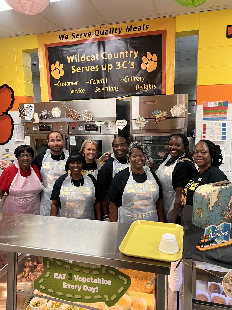 Group photo of transportation dept workers in the cafeteria wearing aprons 