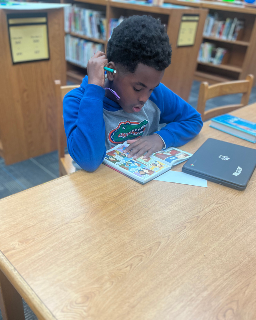 Student reading at a table in the library