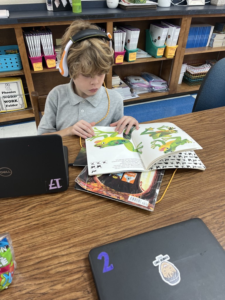 Student reading at a table with headphones on