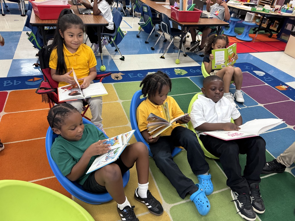 Students reading in small chairs on an area rug in classroom