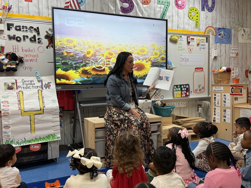 teacher reading to class as they sit on an area rug