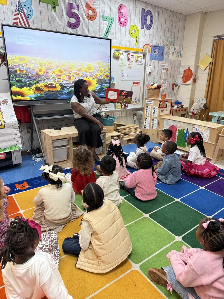 teacher reading to class as they sit on an area rug